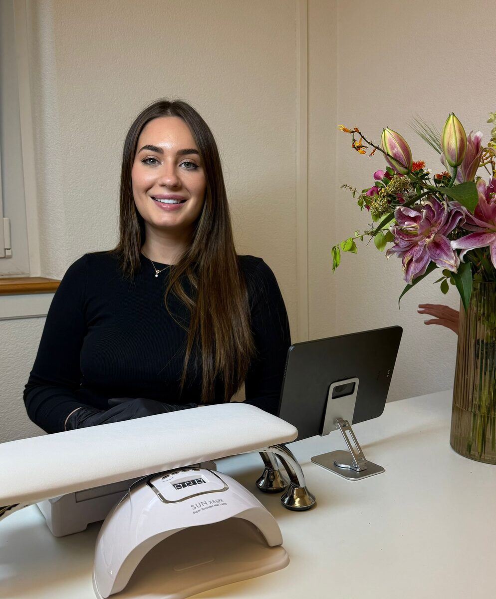 Gabriela Rocha, Inhaberin von Rochela Spa, lächelnd an ihrem Behandlungsplatz mit Blumenstrauss